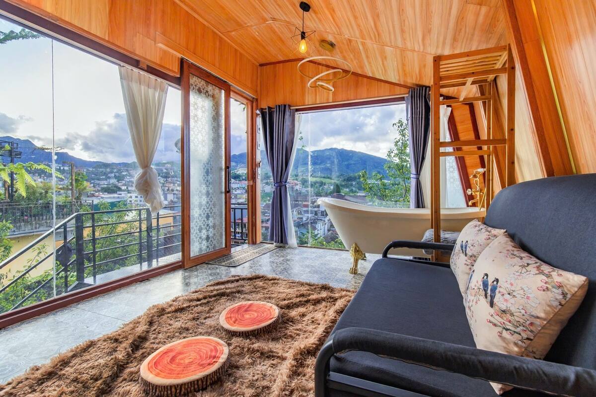 A modern room with a large window, a bathtub, and a sofa with decorative pillows.