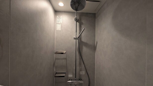 A modern shower with a handheld showerhead, a wall-mounted control panel, and a small shelf. - Hakata no Hatago SUNOYA (Fukuoka)