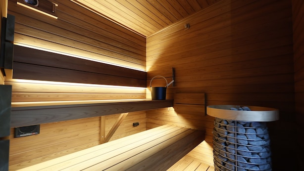 Una sauna de madera con bancos y un cubo.