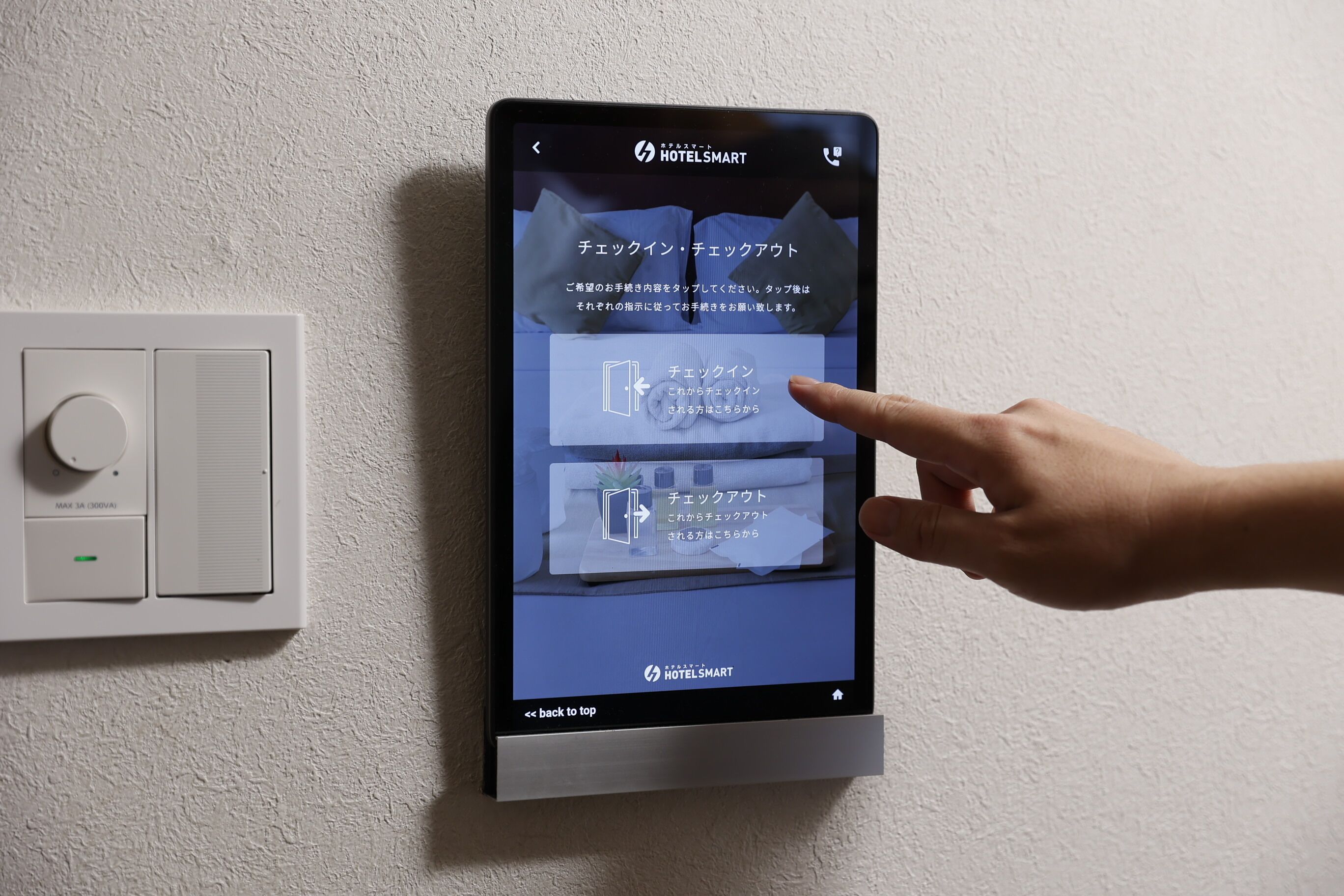 A digital interface on a wall-mounted device displaying hotel information in Japanese.