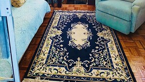 Ein gemütliches Interieur mit einem Bett, einer Couch, einem Esstisch und einem großen Teppich.