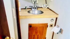 Ein kleines Badezimmer mit einem Holzkosmetikschrank, einem Waschbecken und einer Toilette.