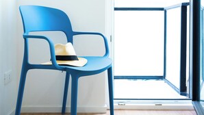 Una habitación con una silla azul, una ventana y una puerta que da al exterior.