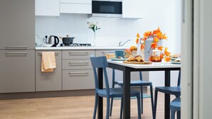 Una cocina moderna con armarios grises, microondas y una mesa de comedor con sillas azules.