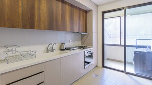 A modern kitchen with white cabinets, stainless steel appliances, and a large window overlooking a balcony. - Crest - 3 Bedroom Apartment in Hamra (Beirut)