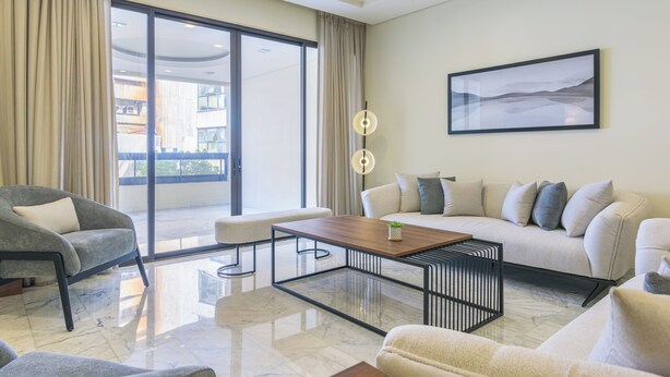 A modern living room with a sofa, armchair, and coffee table. - Crest - 3 Bedroom Apartment in Hamra (Beirut)