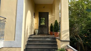 A building entrance with a staircase leading to a door, flanked by potted plants and a balcony with a railing. - VESUVIUS GARDEN 10 MINUTES FROM POMPEI (Boscoreale)