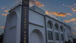 Um edifício com uma placa que diz "Hotel President Park" e céu claro com nuvens.