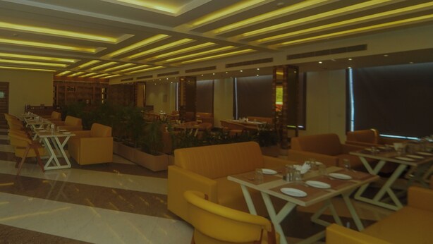 Um restaurante moderno com assentos amarelos, teto estampado e grandes janelas.