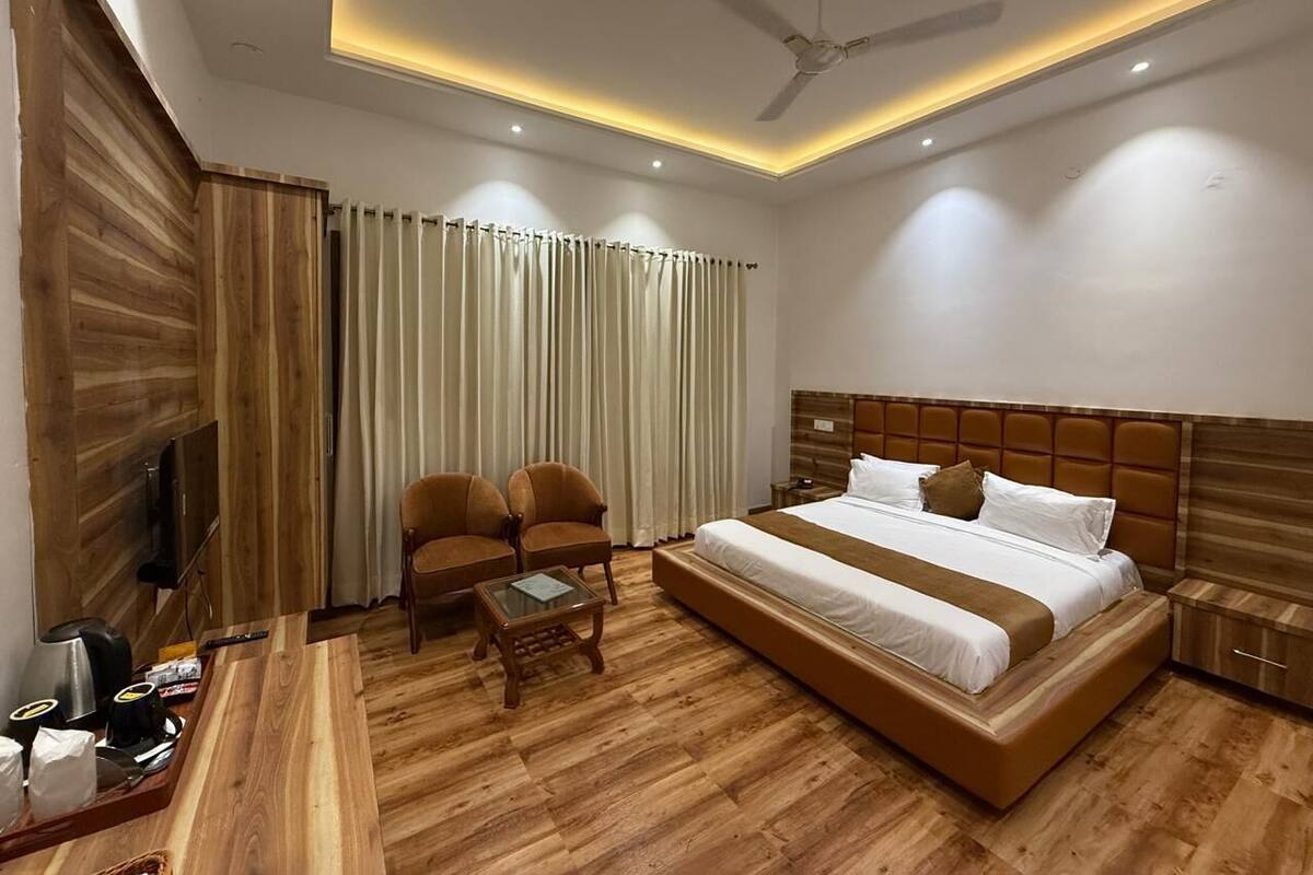 Una habitación de hotel con una cama grande, dos sillones, una mesita de centro, un televisor y un ventilador de techo.