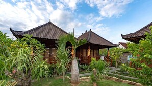 A traditional wooden building with a tiled roof surrounded by lush greenery and a well-maintained garden. - Karang Mas Villa Lembongan (Lembongan Island)