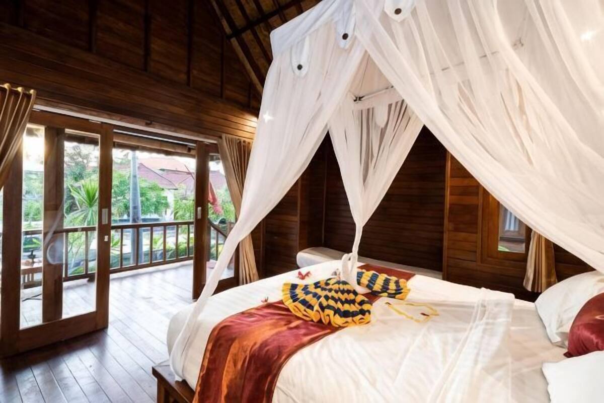 Un dormitorio con cama con dosel, paredes de madera y vistas al exterior.