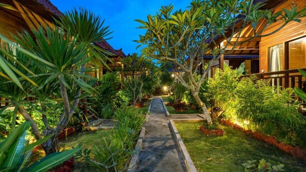 A pathway leading to a row of wooden buildings with a lush garden on either side. - Karang Mas Villa Lembongan (Lembongan Island)