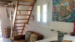 En hyggelig stue med en brun sofa, et glasbord og et farverigt abstrakt maleri på væggen.