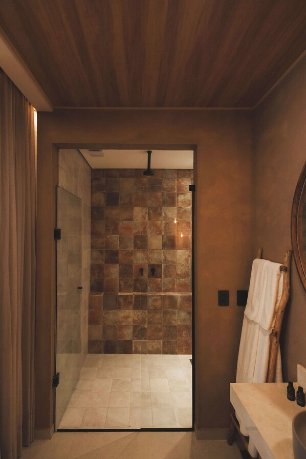 A bathroom with a glass shower enclosure, a wooden ceiling, and a tiled wall. - Casa Mandacaru Noronha (Fernando de Noronha)