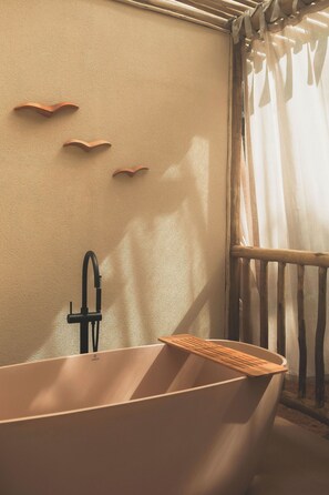 A bathtub with a wooden tray, a black faucet, and a towel rack on the wall.
