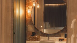 Un baño con un espejo redondo, un lavabo y un perchero para toallas.