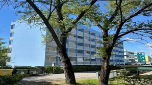 Un edificio moderno con varios pisos y balcones, rodeado de árboles y vegetación.