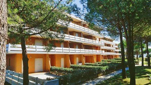 A multi-story hotel with balconies, a covered outdoor seating area, and a well-maintained garden.