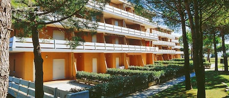 A multi-story hotel with balconies, a covered outdoor seating area, and a well-maintained garden.