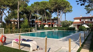 Una piscina con plataforma de madera, rodeada de árboles y edificios.