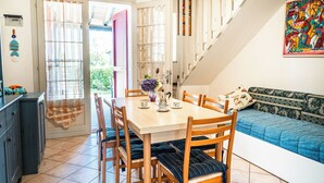 Un área de comedor con una mesa y sillas de madera, un sofá y una escalera.