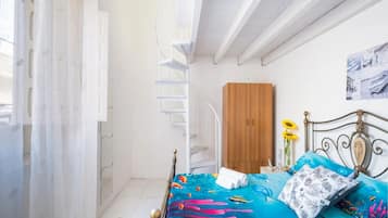 A bedroom with a bed, a wooden wardrobe, a metal bed frame, a patterned rug, and a window with curtains.
