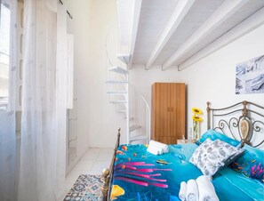 A bedroom with a bed, a wooden wardrobe, a metal bed frame, a patterned rug, and a window with curtains. - Vista Sul Blu Private Residence 3 (Porto Cesareo)