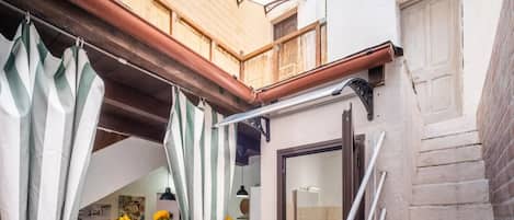 Et kompakt køkken med spiseplads, en træbalcon og et badeværelse med et stort spejl.