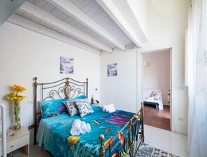 A bedroom with a bed, a nightstand, a vase with flowers, and two wall art pieces. - Vista Sul Blu Private Residence 3 (Porto Cesareo)