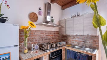 A kitchen with a brick backsplash, wooden cabinets, a stainless steel range hood, and a sink.