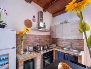 A kitchen with a brick backsplash, wooden cabinets, a stainless steel range hood, and a sink. - Vista Sul Blu Private Residence 3 (Porto Cesareo)