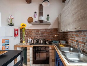 A kitchen with a brick backsplash, stainless steel appliances, and a wooden countertop. - Vista Sul Blu Private Residence 3 (Porto Cesareo)