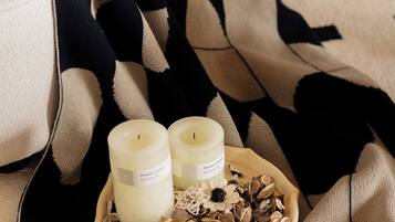 Ambiente acogedor con una manta, velas y flores secas sobre una bandeja.