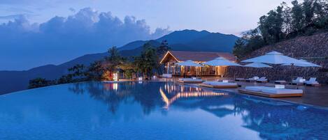 Una piscina al aire libre, sombrillas, sillones reclinables de piscina