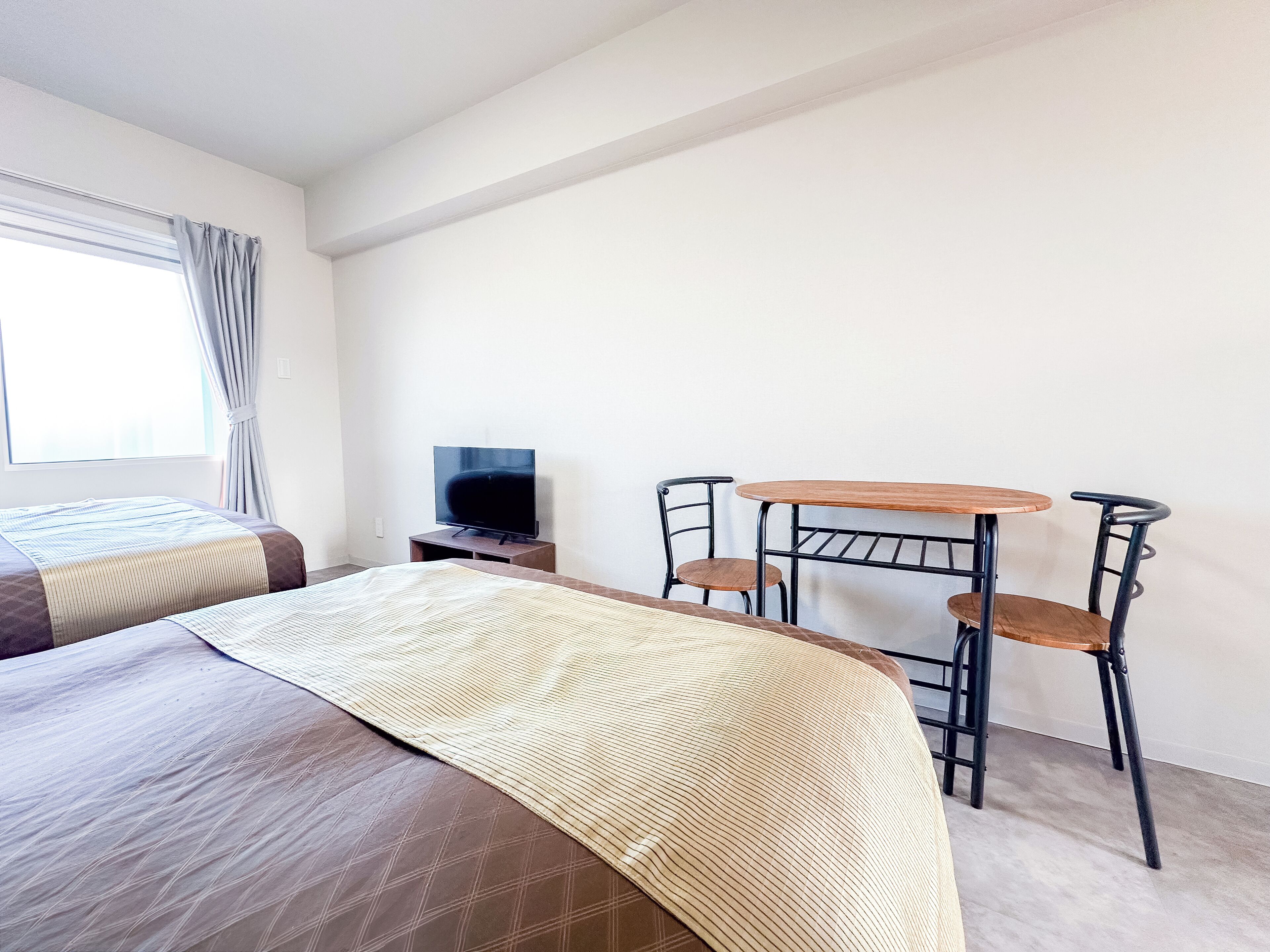 Una habitación de hotel con cama, televisión, una mesita y dos sillas.