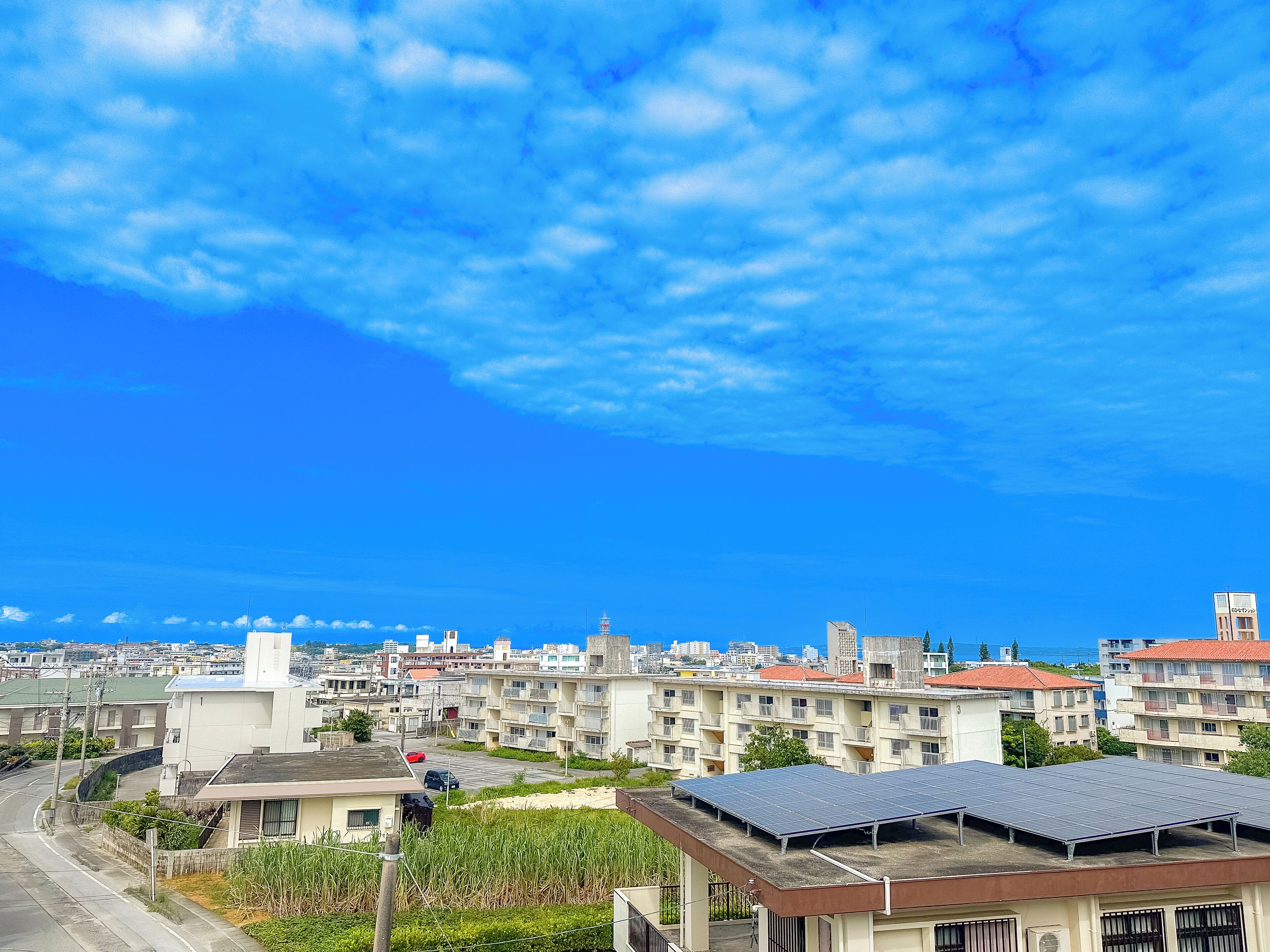 A residential area with multiple buildings, a clear sky, and a road.