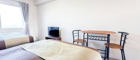 A hotel room with a bed, a TV, a small table, and two chairs.