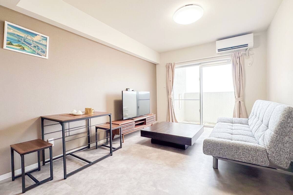 Una sala de estar moderna con un sofá, una mesa de centro, un televisor y una mesita con una bandeja.