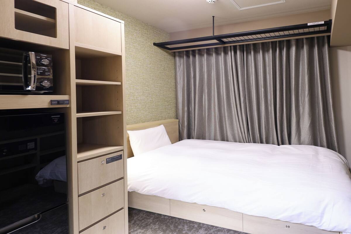 Una habitación de hotel con cama, televisor, armario y un pequeño escritorio.