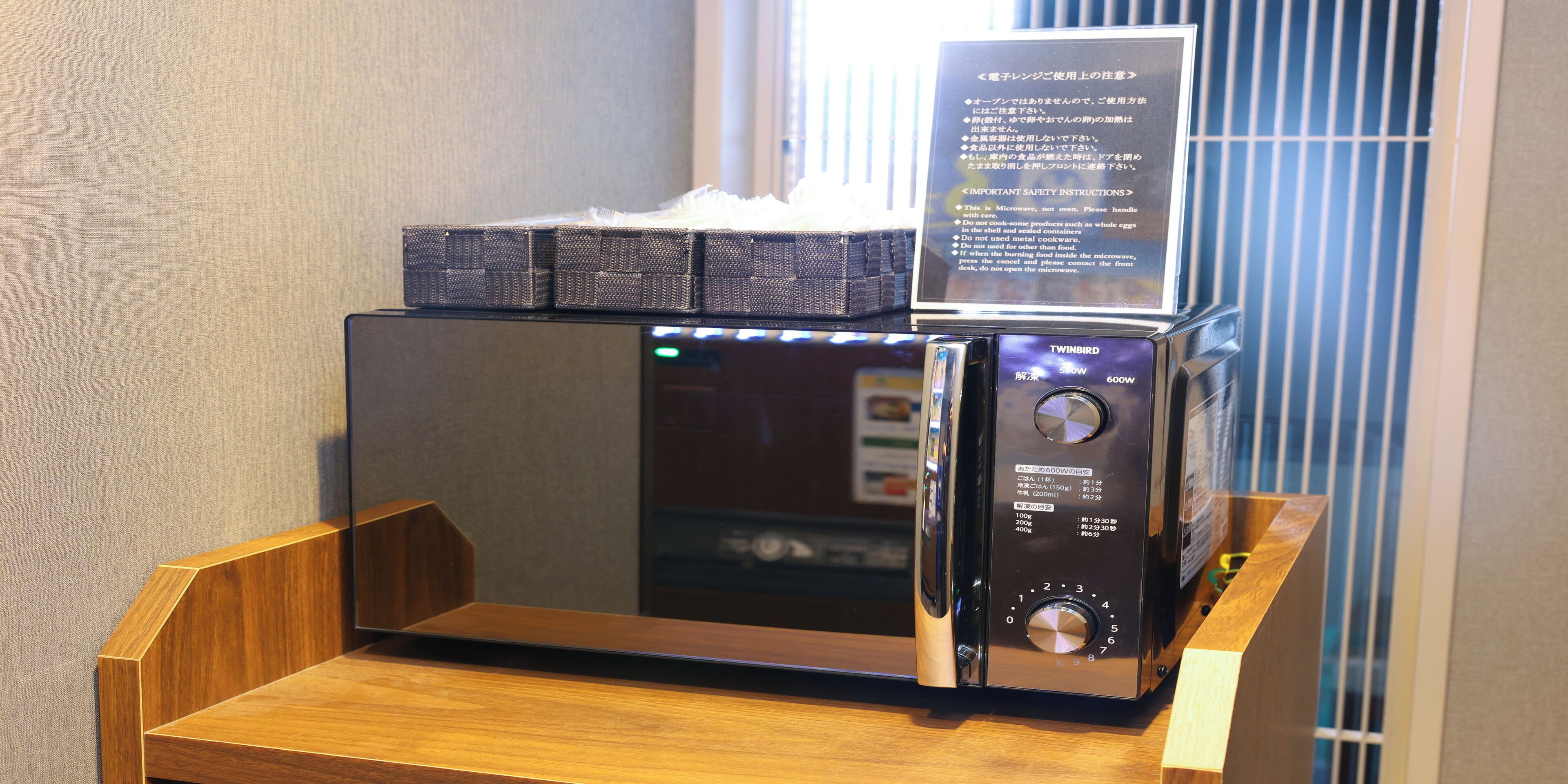 A microwave oven with a digital display and control panel, placed on a wooden surface.