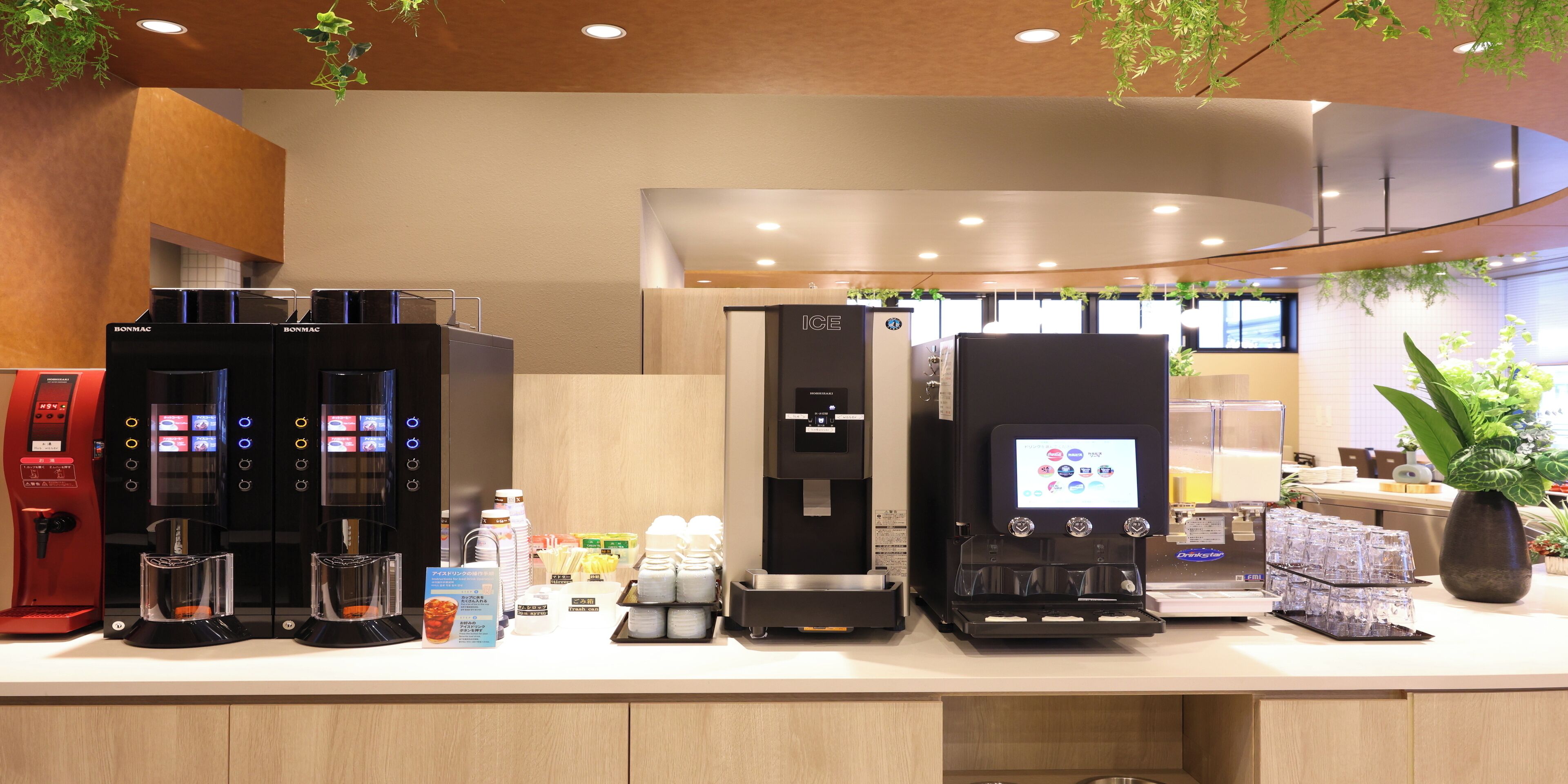 A coffee station with multiple machines, a beverage dispenser, and a selection of cups and containers.