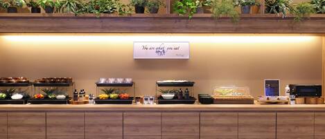 A buffet setup with various food items, a sign, and a microwave.