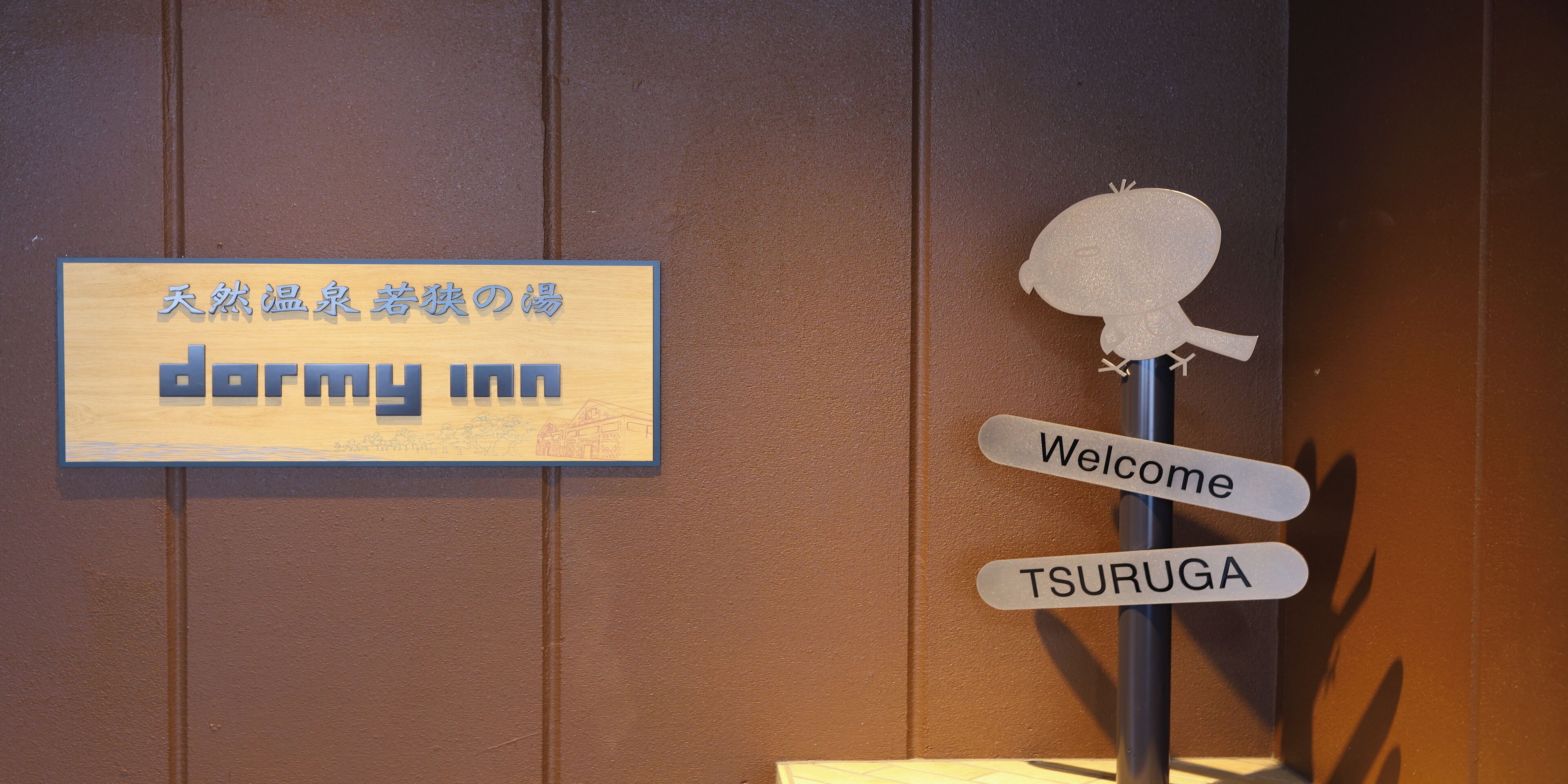 Un letrero de bienvenida con una decoración de calavera y un cartel para 'dormy inn' con texto en japonés.