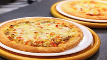 Dos pizzas sobre platos blancos con aros amarillos, sobre una superficie oscura.