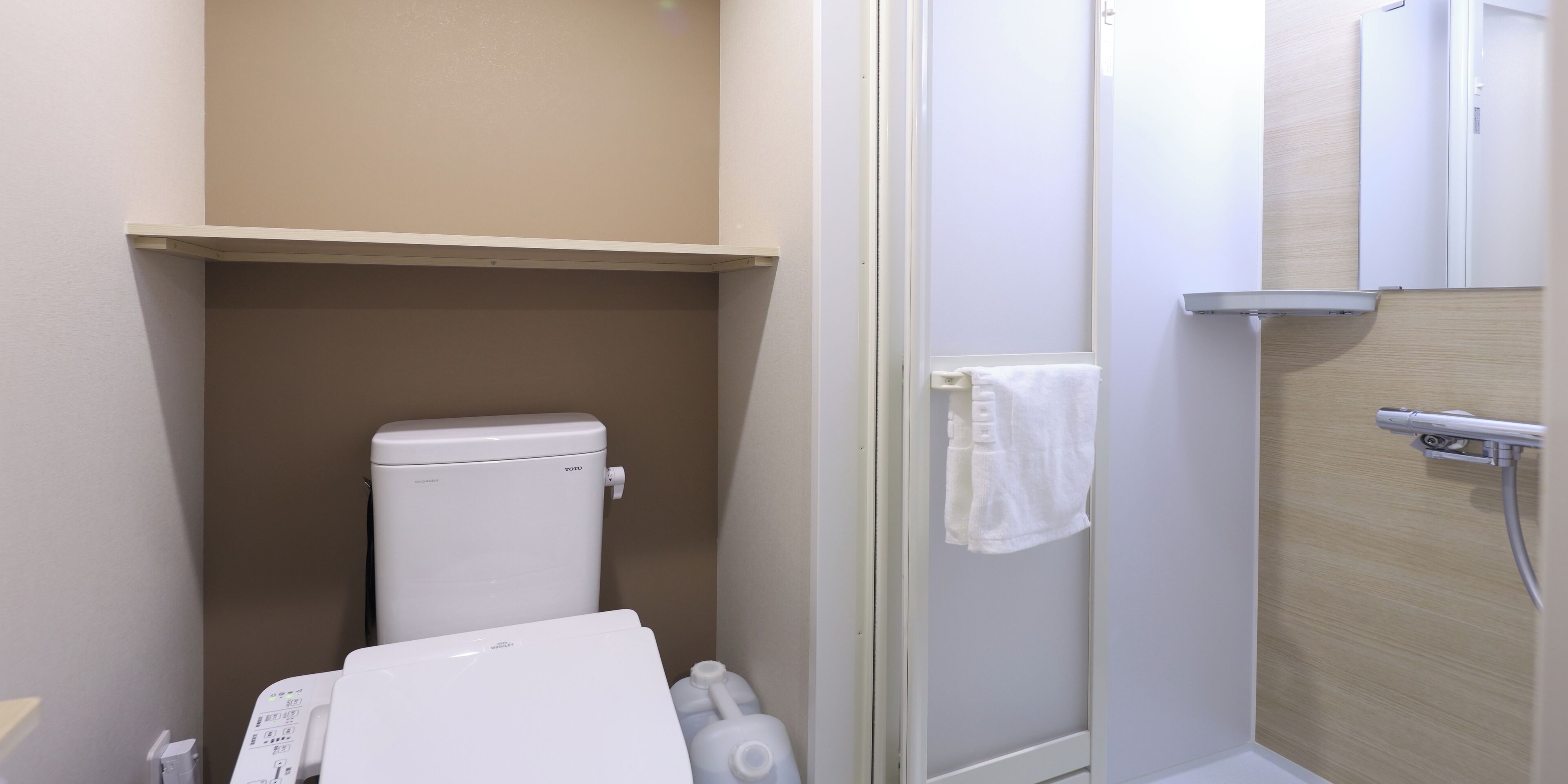 Un baño pequeño con inodoro, ducha y barra para toallas.