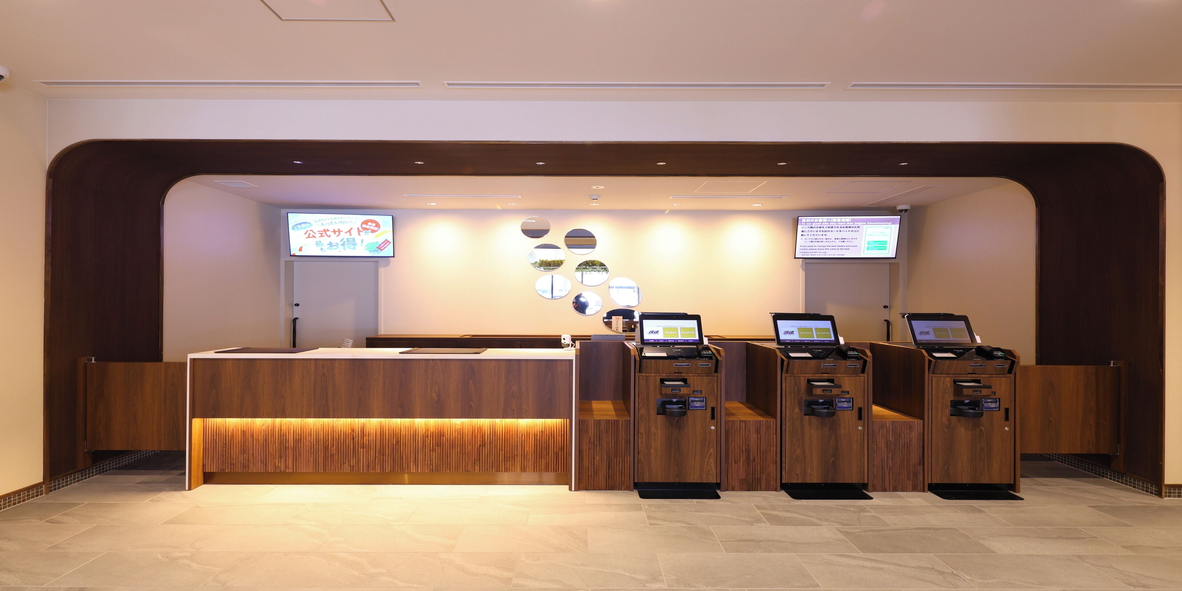 A reception area with a wooden reception desk, two computer stations, and a digital display.
