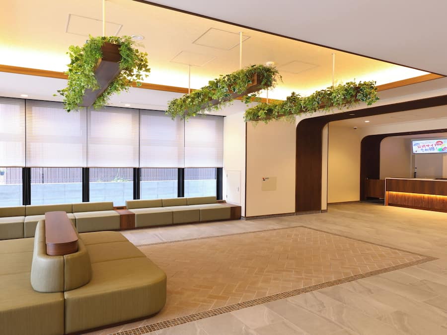 A spacious lobby with a large seating area, a reception desk, and a television screen.