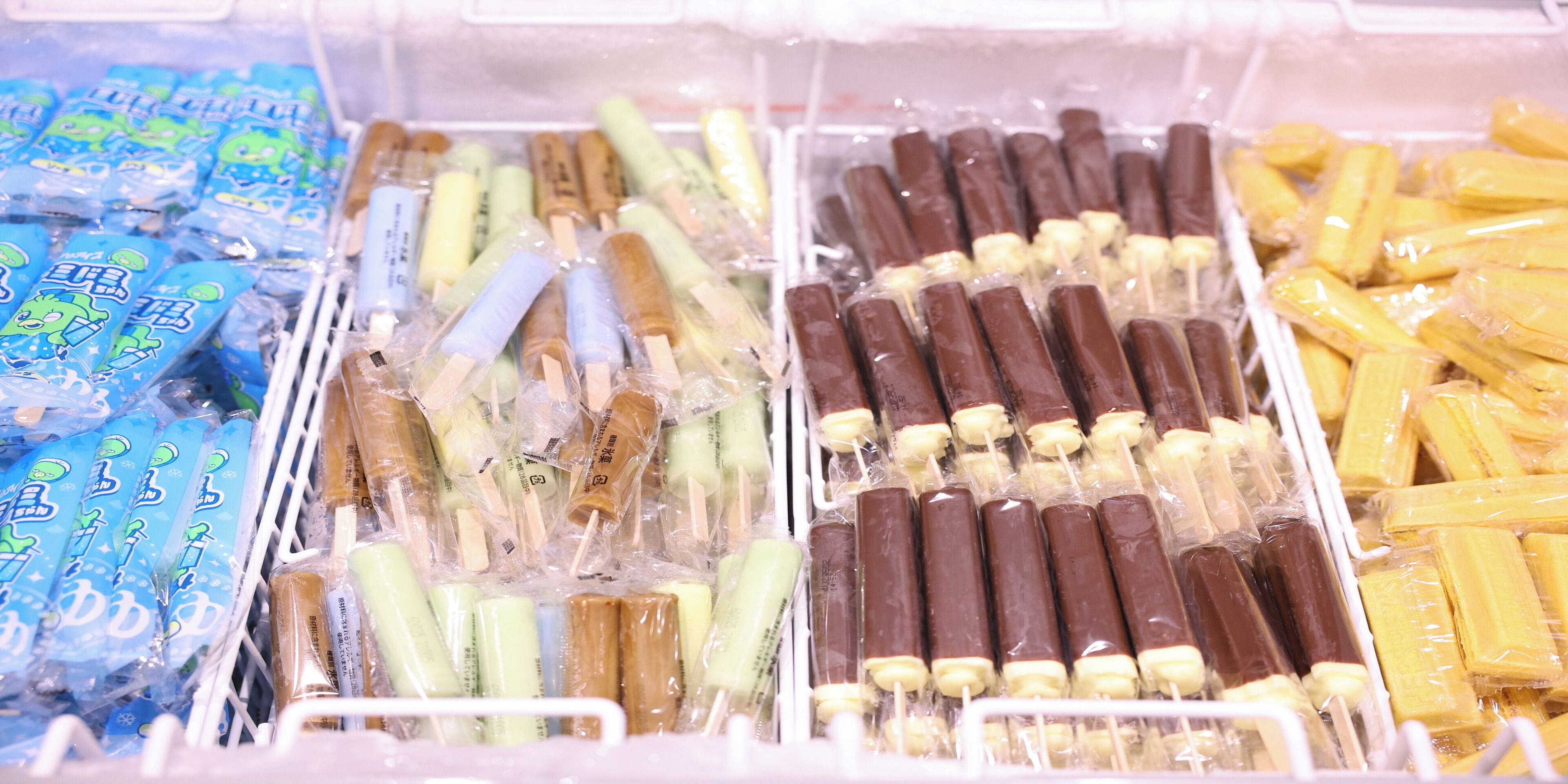 A freezer with various frozen treats, including popsicles and ice cream bars.