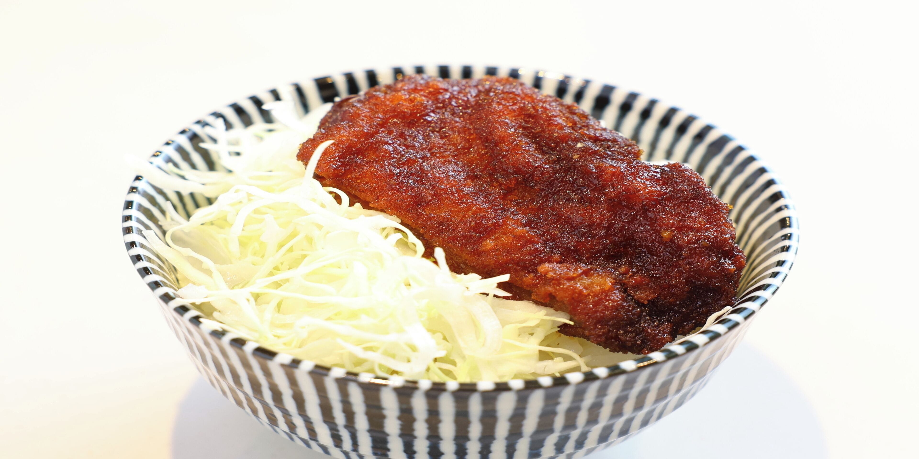 A bowl containing a fried item and shredded cabbage.